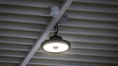 Das Bild zeigt eine Decke mit Holzstreben, an der ein runder Hallenstrahler aus der Serie LIGHTSHOWERsmart hängt