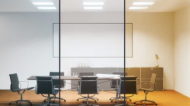 Moderner Konferenzraum mit Tisch und Stühlen. Blick von außen durch eine große Glasfront.