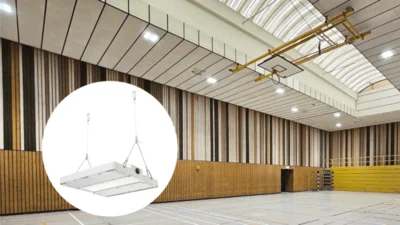 Das Bild zeigt eine moderne Sporthalle mit Holzvertäfelung unterschiedlicher Struktur und Farbe. Unter dem Dach ist ein Basketballnetz an einem Metallgestänge hochgeklappt. Hallenstrahler der Serie Lightbeam beleuchten den Raum. In der linken unteren Bild-Ecke ist in einem weißen Kreis die Hallenleuchte Lightbeam abgebildet. 