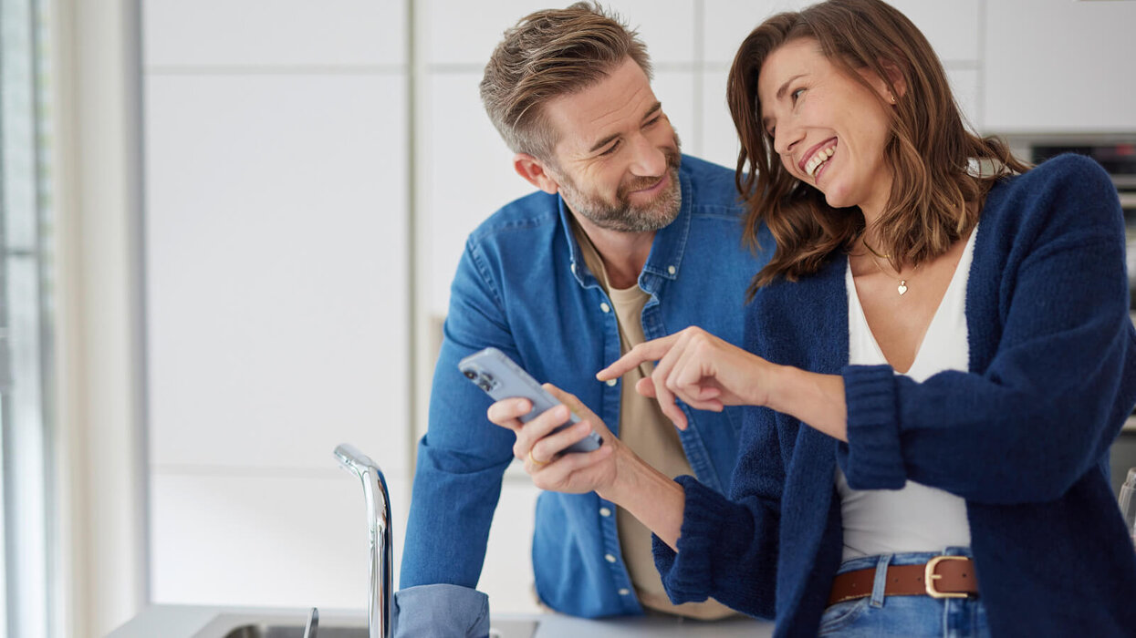 Mann und Frauen schauen gemeinsam auf das Smartphone und lachen dabei.