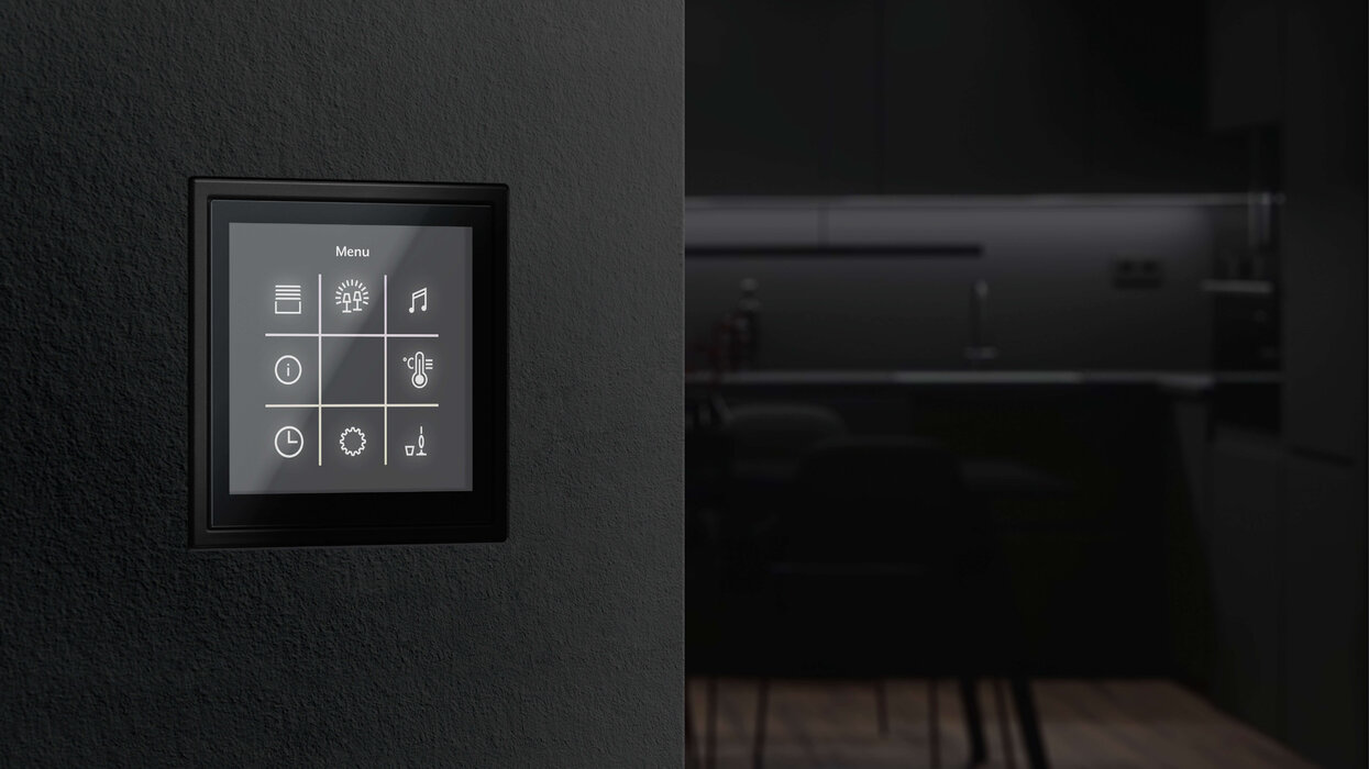 Dunkles Bedienfeld mit Touchscreen an einer ebenfalls dunklen Wand in der Farbe Schwarz.