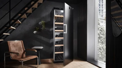 Stilvoller und in der Farbe Schwarz gehaltener Wohnraum mit großem Weinlagerschrank in der Farbe schwarz, der geöffnet ist.