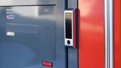 Haustür in der Farbe Grau. Rechts daneben ein Bedienelement für eine Sprechanlage.